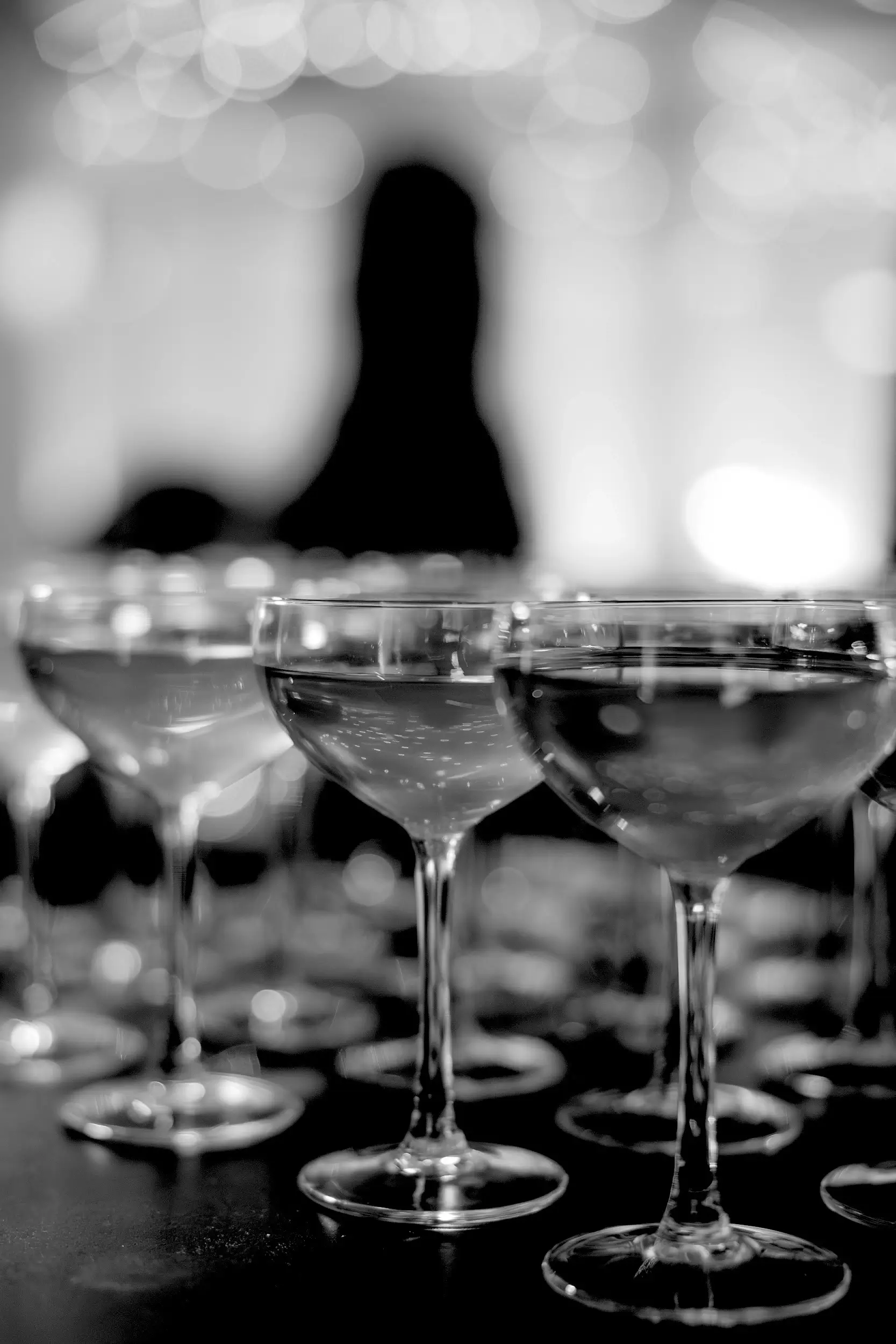 Champagne glasses in a row on a table in a black and white mood, highlighting an elegant table setting.